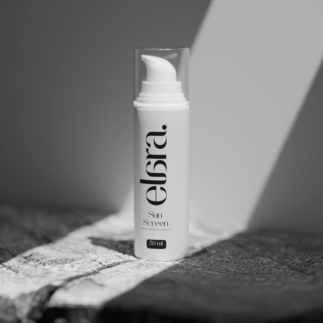 Elara sunscreen bottle on a textured surface with a blurred background